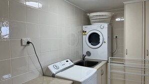 A compact laundry room with a washing machine, a dryer, and a utility sink.
