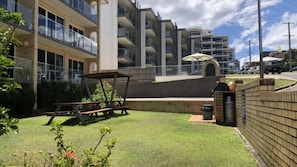 Un edificio residencial con varios balcones, un patio con mesa y sillas, y un muro de ladrillo.