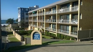 Un hotel de varios pisos con un letrero que indica 'Holiday Units' y un número de contacto.