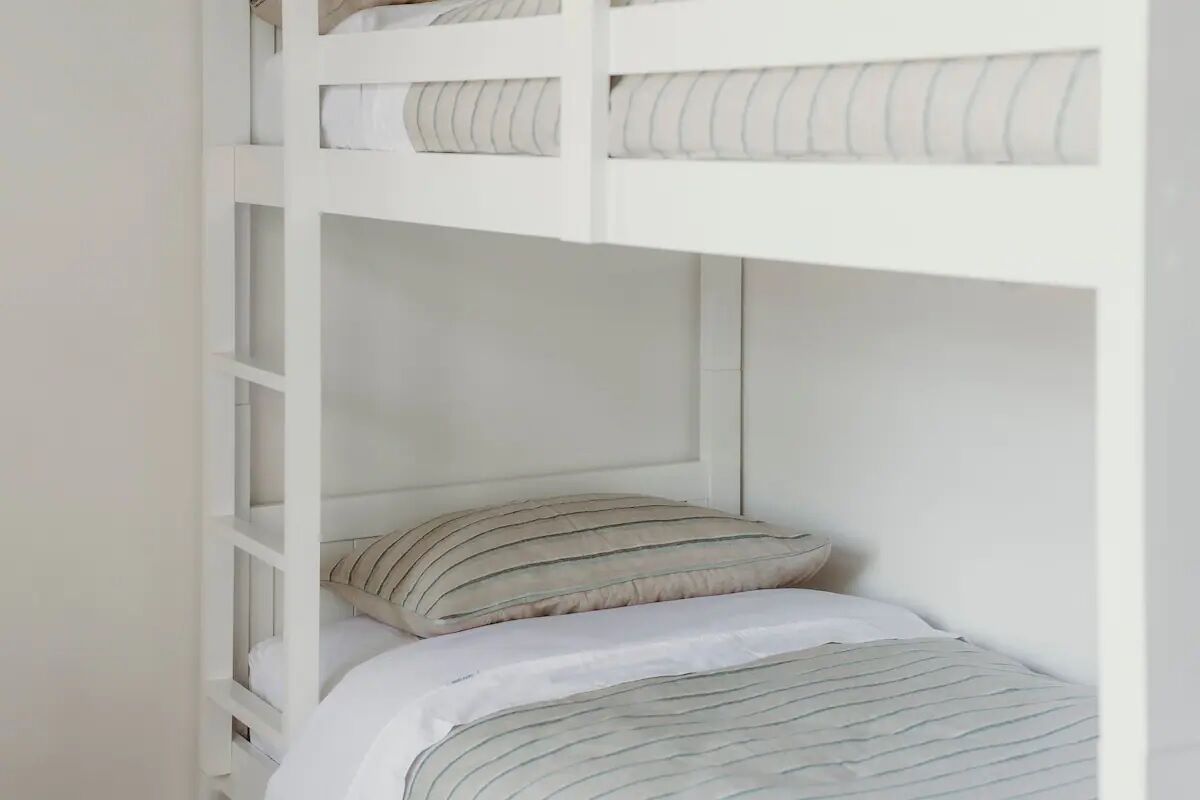 A bunk bed with striped bedding and a white headboard.