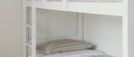 A bunk bed with striped bedding and a white headboard.