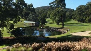 A golf course with a pond, trees, and a small building. - THE BAY. Effortless family fun. Pet friendly. (Nelson Bay)