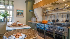Una cucina con fornello, forno e utensili da cucina appesi.
