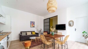 Una sala de estar moderna con sofá, mesa de comedor, sillas y televisor.