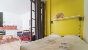 Una habitación de hotel con cama, escritorio, silla y kitchenette.