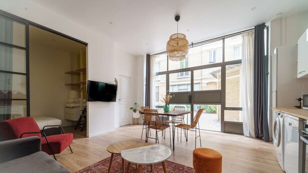 Una sala moderna con un sofá, una mesa de centro y un comedor con sillas.