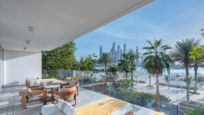 Een modern balkon met uitzicht op de stad, gemeubileerd met een bank, stoelen en een eettafel.