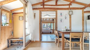 A rustic wooden interior with a dining area, a bench, and a view through a doorway. - Jeju Motungedoljib Dogchaepension (Jeju City)
