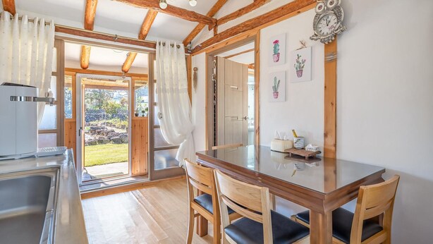 A kitchen with a sink, a coffee machine, and a window overlooking a garden. - Jeju Motungedoljib Dogchaepension (Jeju City)