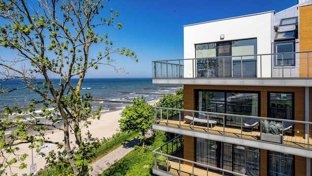 Een modern gebouw met een balkon met uitzicht op een strand en zee.
