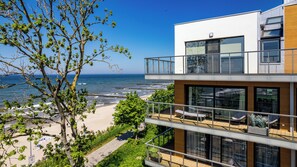 A modern building with a balcony overlooking a beach and ocean. - Prywatne apartamenty Sun&Snow w obiekcie Ustronie Apartments (Ustronie Morskie)