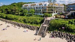 Hotel aan het strand met meerdere balkons, een houten steiger en een zandstrand.