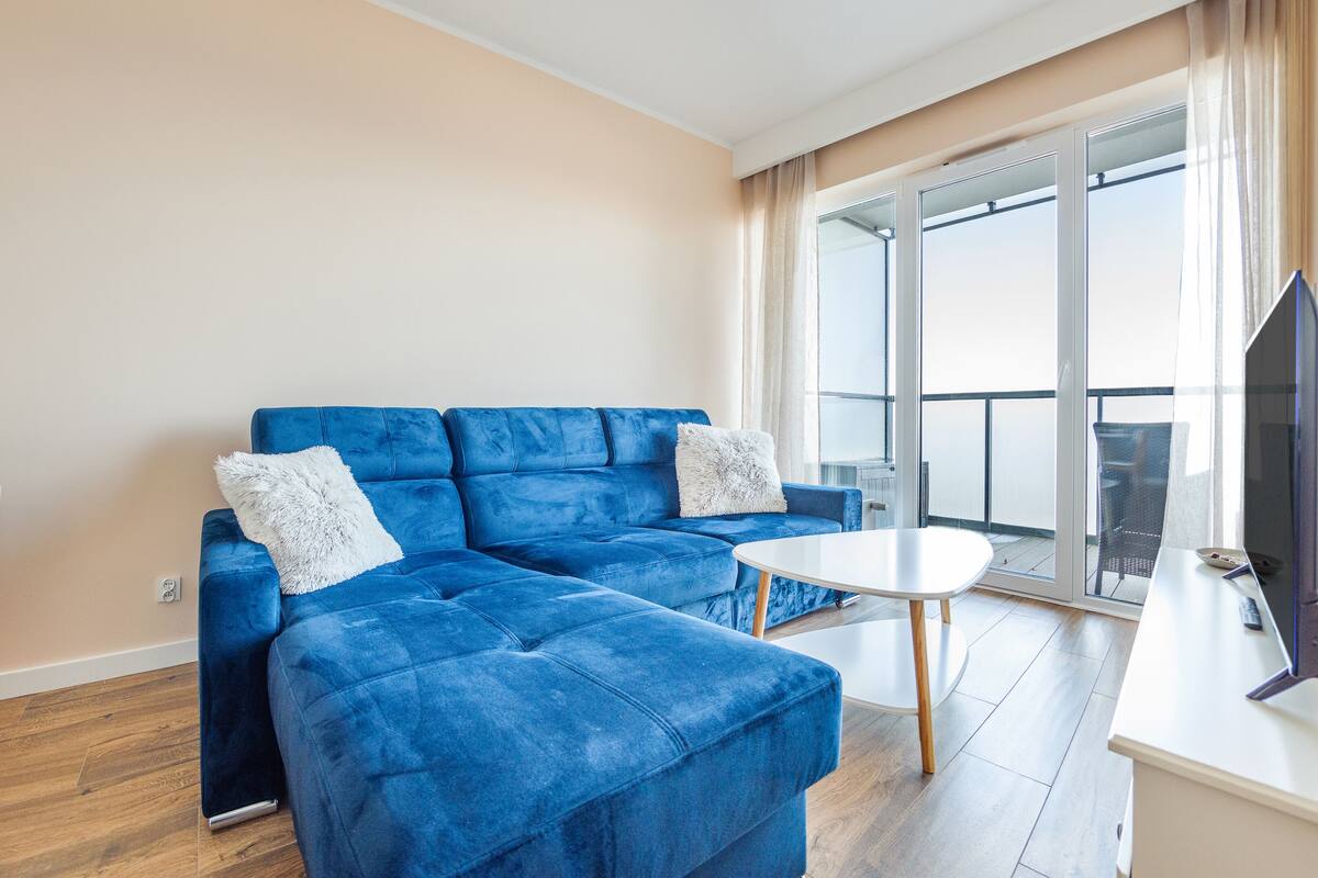 Ein modernes Wohnzimmer mit einem blauen Sofa, einem weißen Couchtisch und einem Flachbildfernseher.