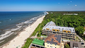 Een hotel aan de kust met meerdere verdiepingen, uitzicht op het strand en zonnepanelen op het dak.