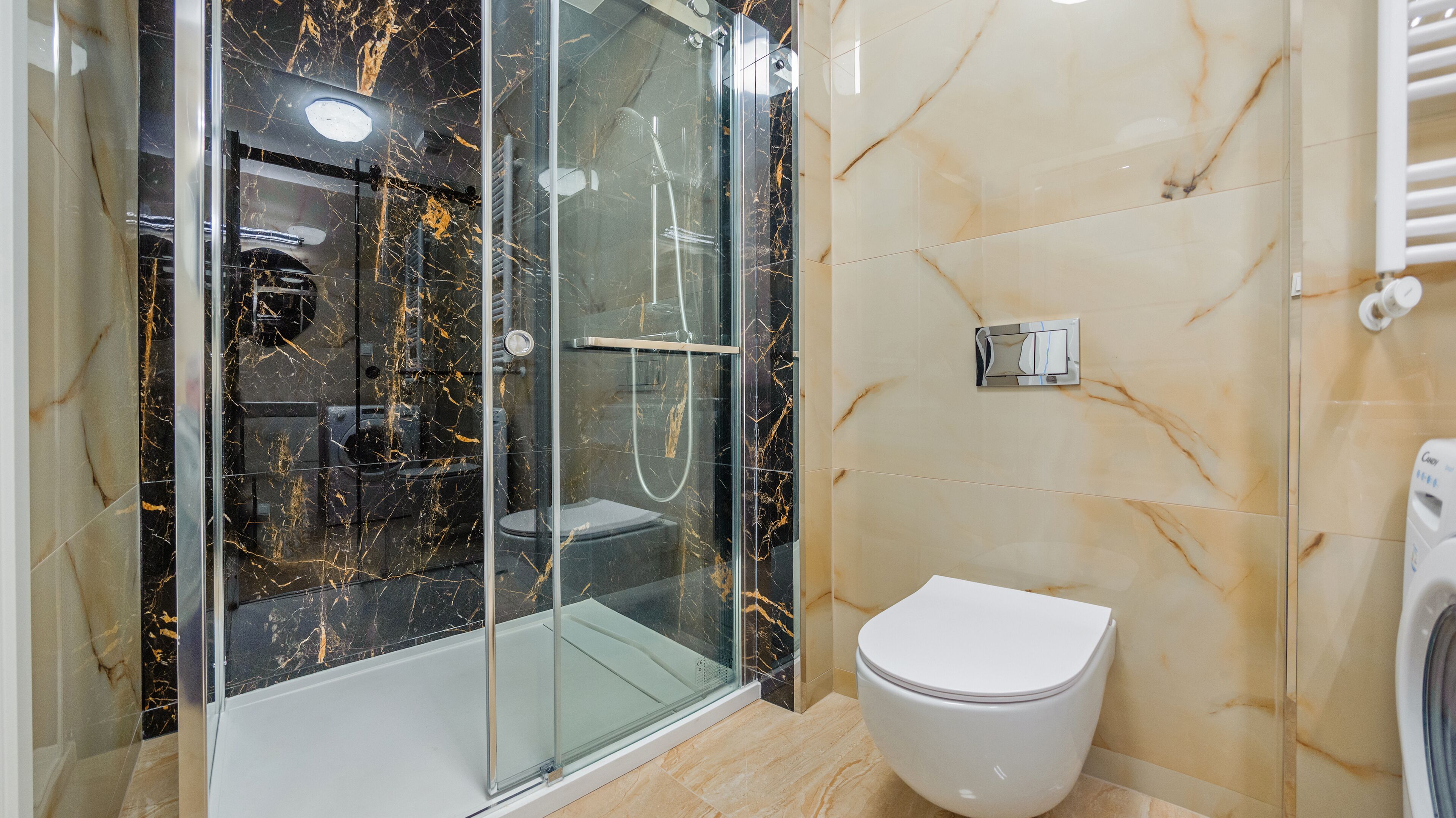 A modern bathroom with a glass-enclosed shower, a toilet, and a hand dryer.
