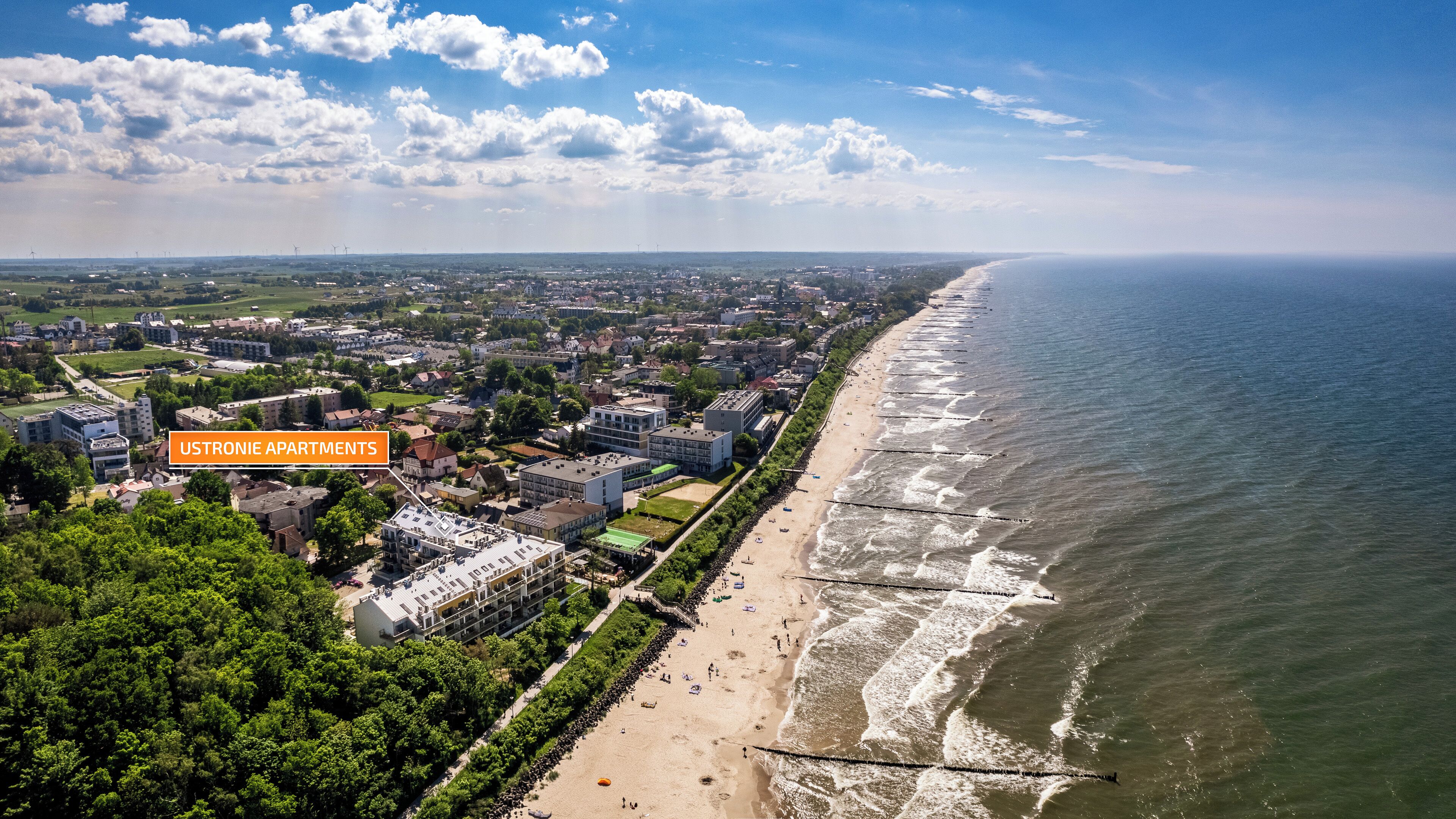 A coastal cityscape with a beachfront, including a hotel named USTRONIE APARTMENTS.