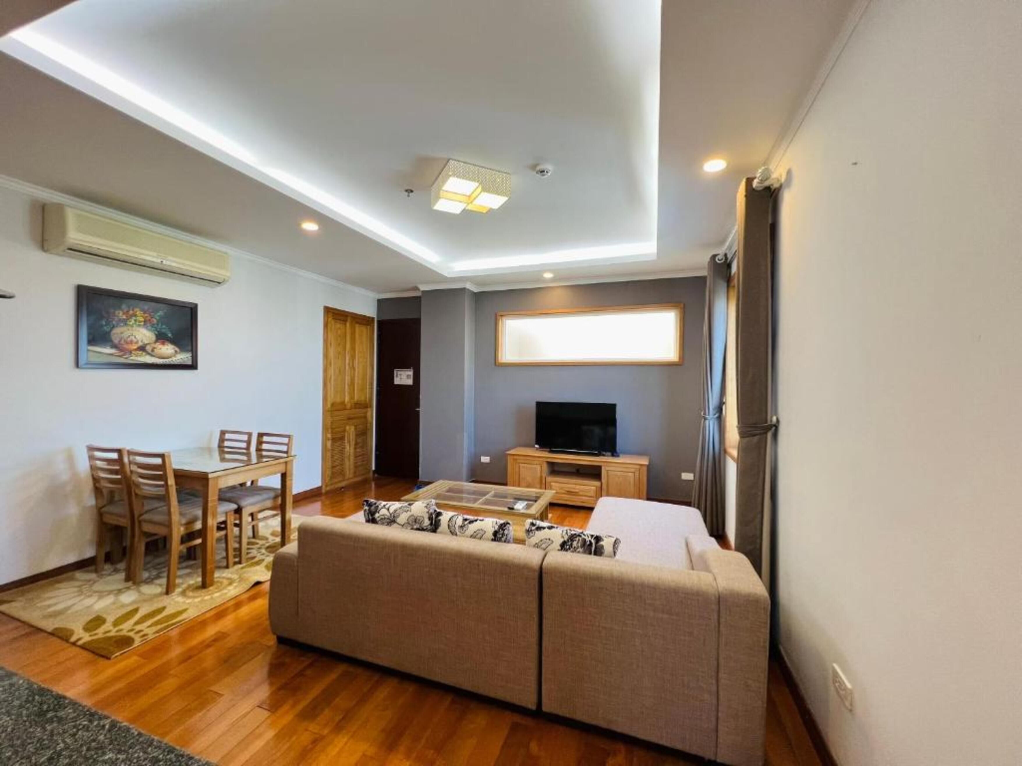 A modern living room with a sofa, TV, and dining area.
