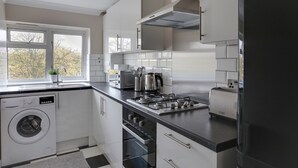 A modern kitchen with a built-in washer, a stove, and a toaster. - BookedUK - Bright flat in Harlow (Harlow)