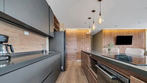 A modern kitchen with a built-in oven, a coffee machine, and a flat-screen TV mounted on the wall. - Olive 301 · Amazing 2BR Luxury Apt in Alto Las Palmas (Alto Palmas)