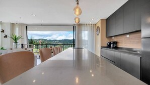A modern kitchen with a large island, stainless steel appliances, and a view of the countryside. - Olive 301 · Amazing 2BR Luxury Apt in Alto Las Palmas (Alto Palmas)
