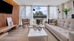 A modern living room with a sofa, armchair, coffee table, and a TV mounted on the wall. - Olive 301 · Amazing 2BR Luxury Apt in Alto Las Palmas (Alto Palmas)