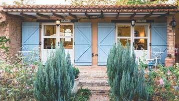 A building with two blue doors labeled 'Blue Moon 1' and 'Blue Moon 2,' a stone staircase, and a garden with potted plants.