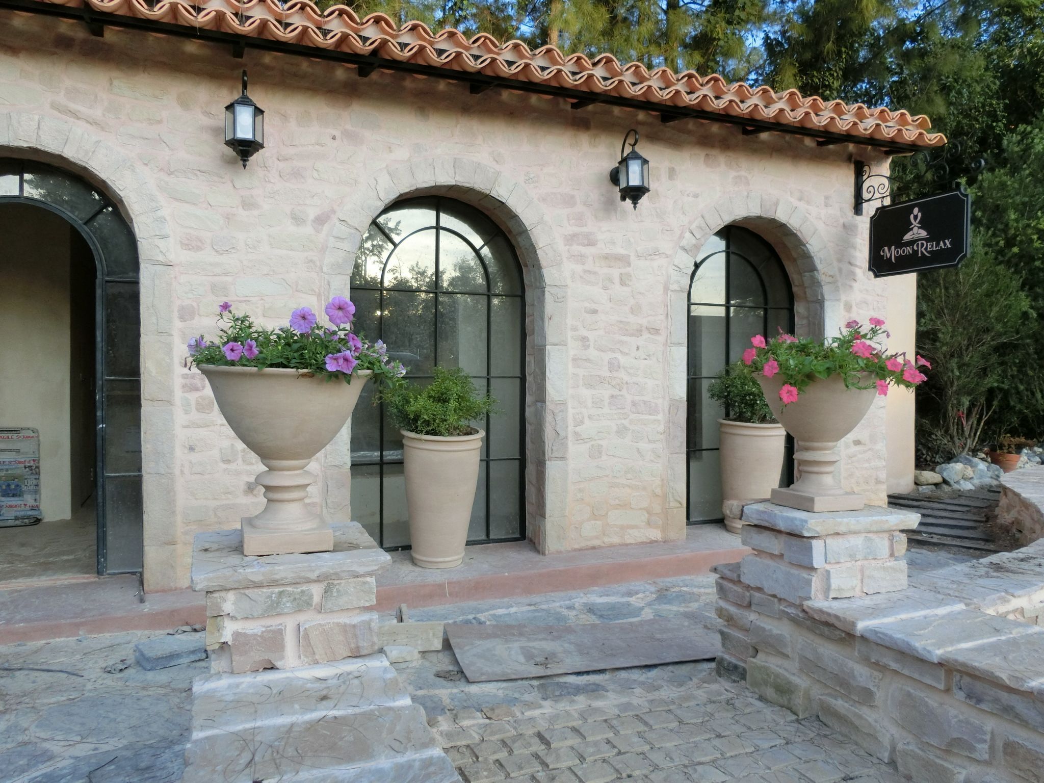 Un edificio con tres ventanas arqueadas, techo de tejas y un letrero que dice "Moon Relax".