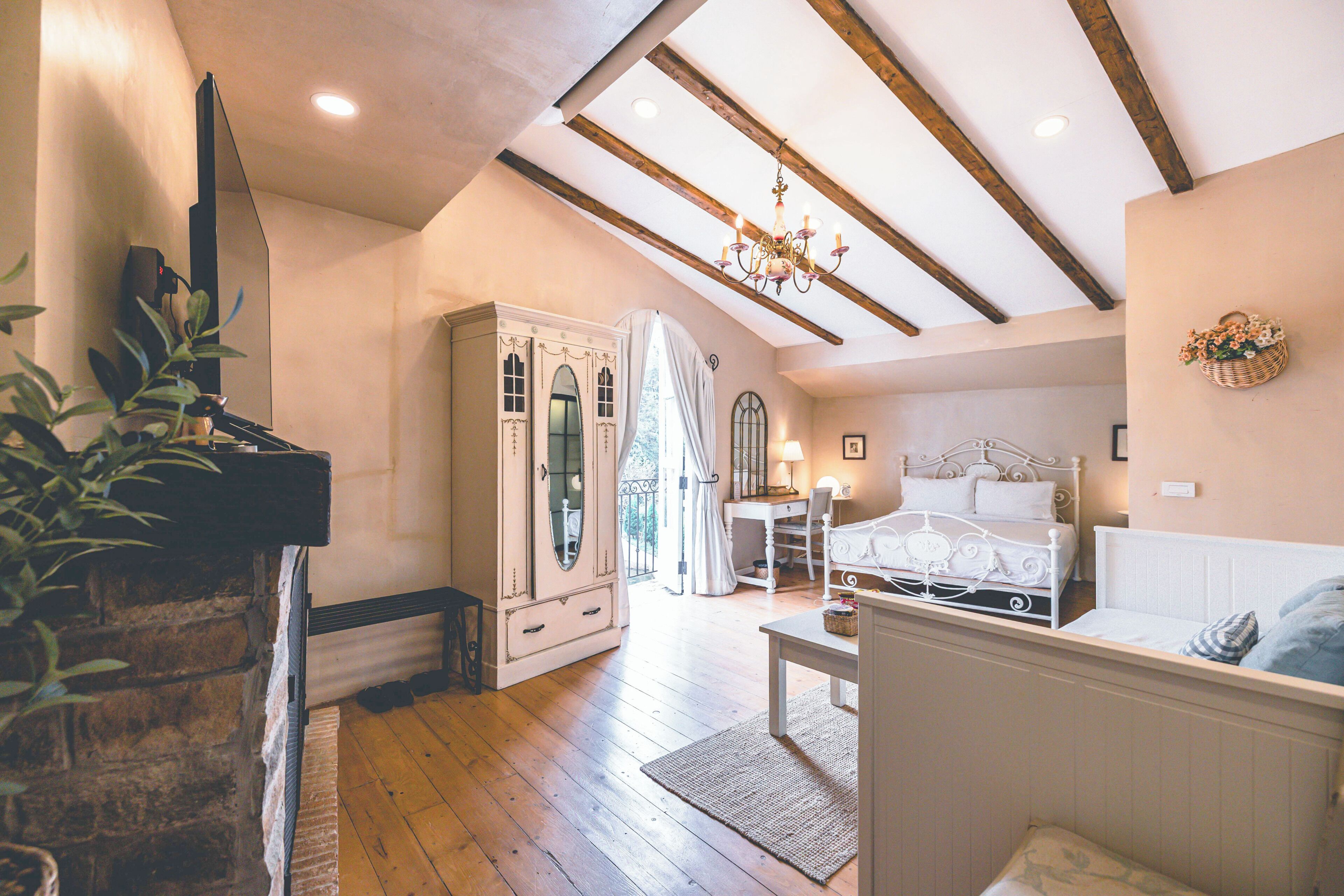 A bedroom with a bed, a desk, a chair, a dresser, and a chandelier.