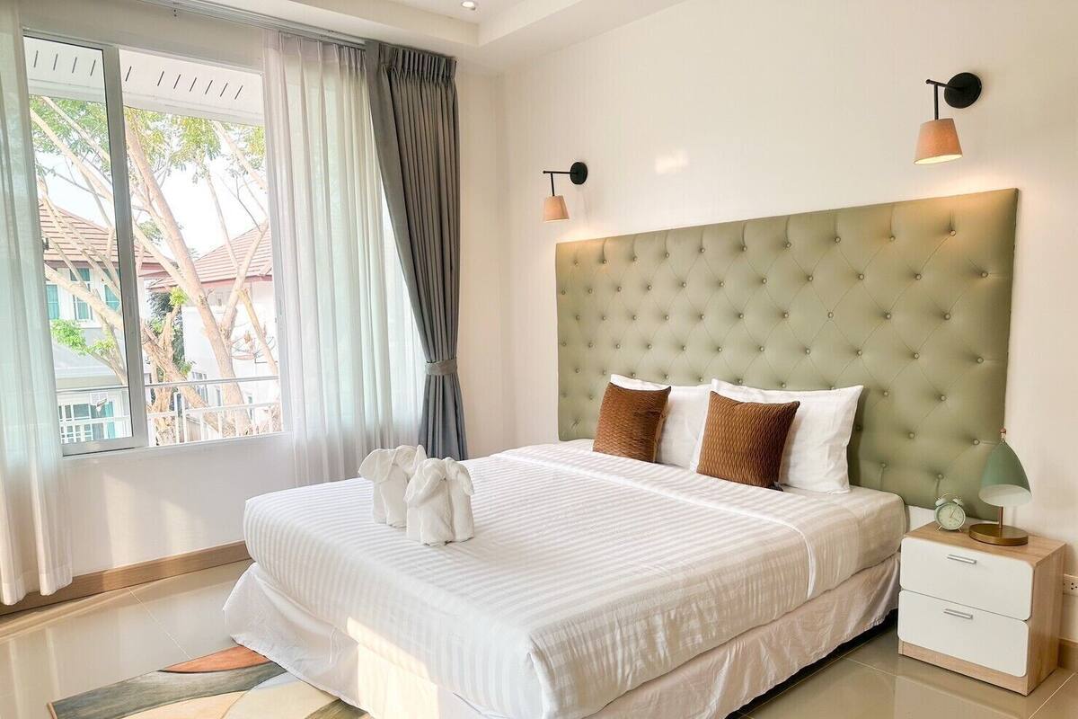 Une chambre d’hôtel avec un grand lit, une table de chevet, une lampe et une vue sur l’extérieur.