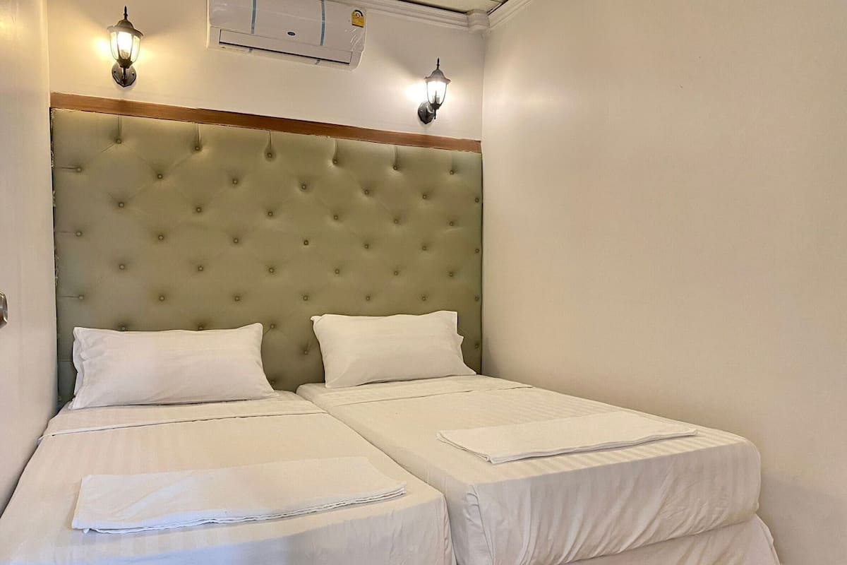 Un lit double avec une tête de lit capitonnée, deux tables de chevet et des appliques murales.