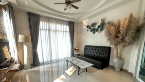 Una sala de estar moderna con un sofá negro, una mesa de centro de mármol y una pieza decorativa en la pared.