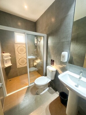 A modern bathroom with a glass shower enclosure, a toilet, a sink, and a trash bin. - Marc Hotel Maesai (Mae Sai)