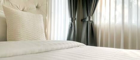Una cama bien hecha con un cabecero capitonado y una única almohada decorativa.