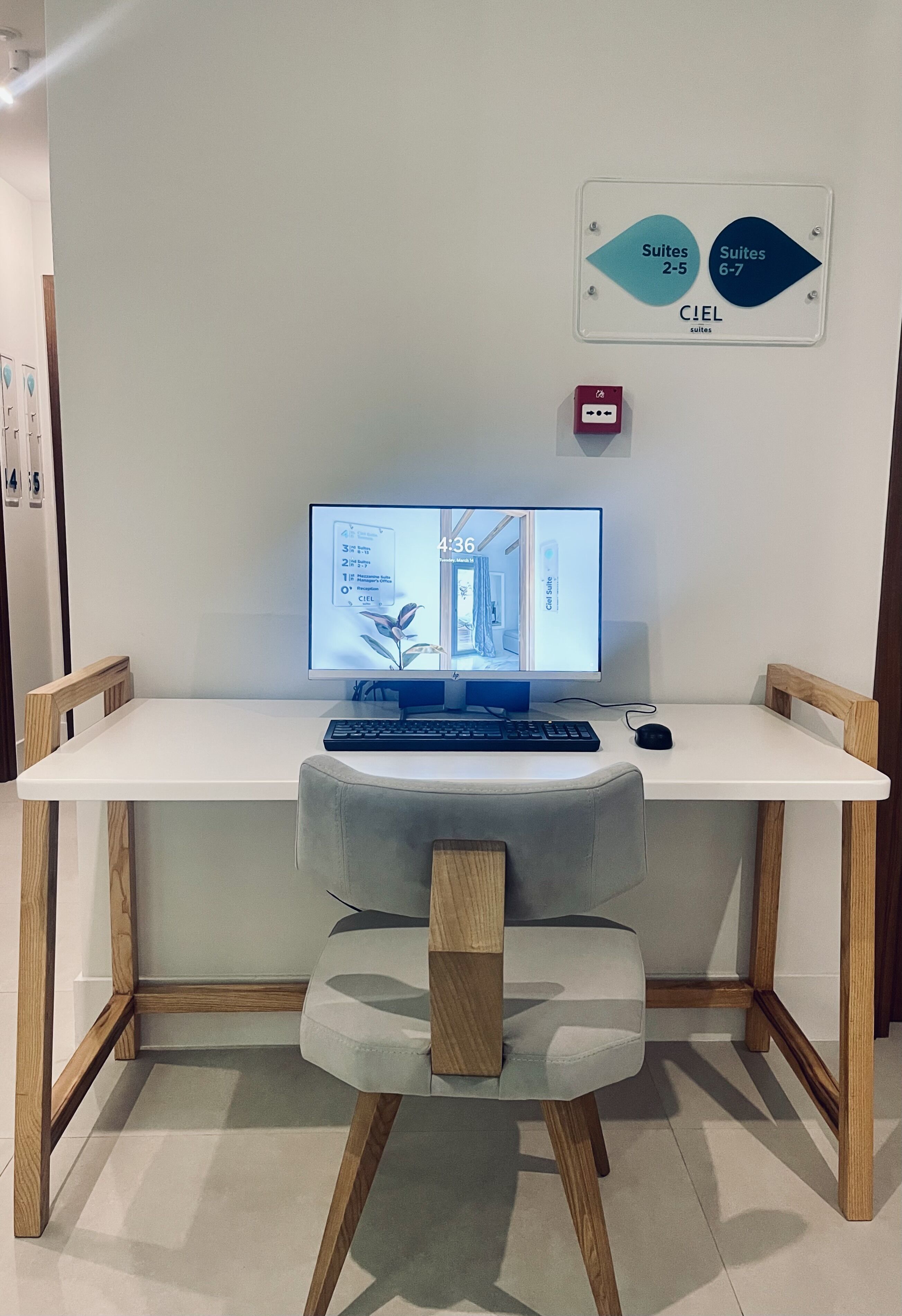 A modern desk setup with a computer, chair, and a sign indicating room numbers.