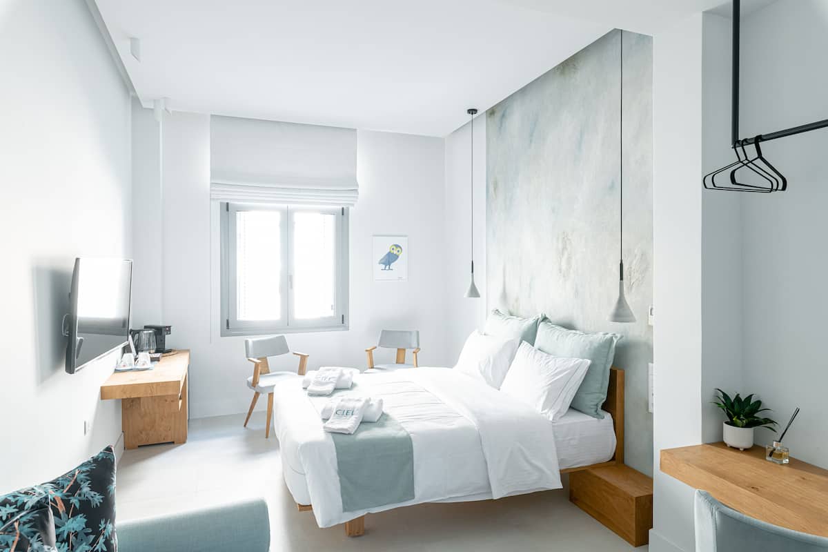 Quarto moderno com uma cama grande, uma escrivaninha, uma cadeira e uma televisão.