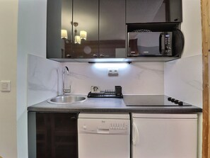 A compact kitchen with a built-in microwave, a dishwasher, and a sink.