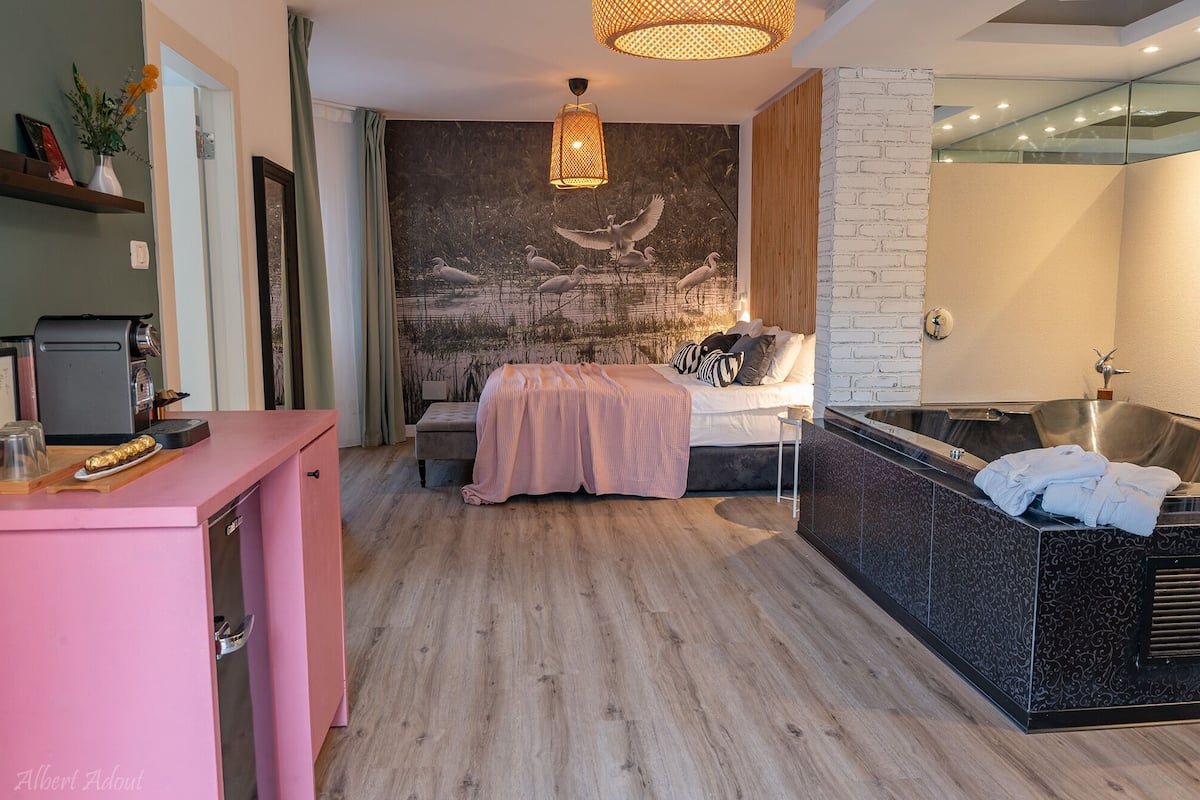 Een moderne slaapkamer met een groot bed, een zithoek, een koffiezetapparaat en een badkuip.