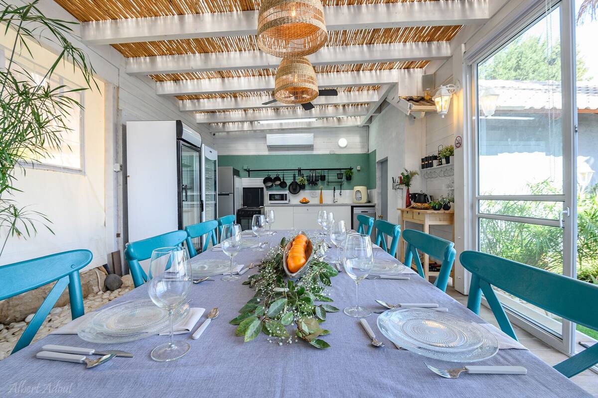 Een eethoek met een lange tafel voor zes personen, blauwe stoelen en een plafond met geweven patronen.