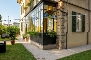 A building with a glass exterior, stone facade, and green shutters. - Villa Romantica (Lucca)