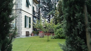 A building with a stone facade, a well-maintained lawn, and various potted plants. - Villa Romantica (Lucca)