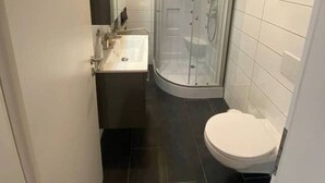 A modern bathroom with a glass-enclosed shower, a sink, and a toilet. - Cozy Studio 2 Rosenburgblick near the Moselle (Zeltingen-Rachtig)
