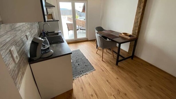A compact kitchen with a dining area, a large window, and a view of the outdoors. - Cozy Studio 2 Rosenburgblick near the Moselle (Zeltingen-Rachtig)