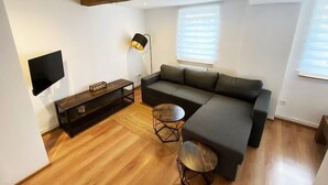 A modern living room with a sectional sofa, a coffee table, and a TV mounted on the wall. - Cozy Studio 2 Rosenburgblick near the Moselle (Zeltingen-Rachtig)
