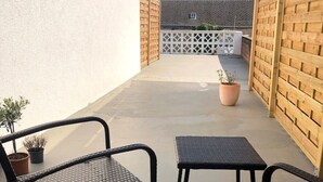 A patio area with two black wicker chairs and a small table, surrounded by a low brick wall and a white fence. - Cozy Studio 2 Rosenburgblick near the Moselle (Zeltingen-Rachtig)
