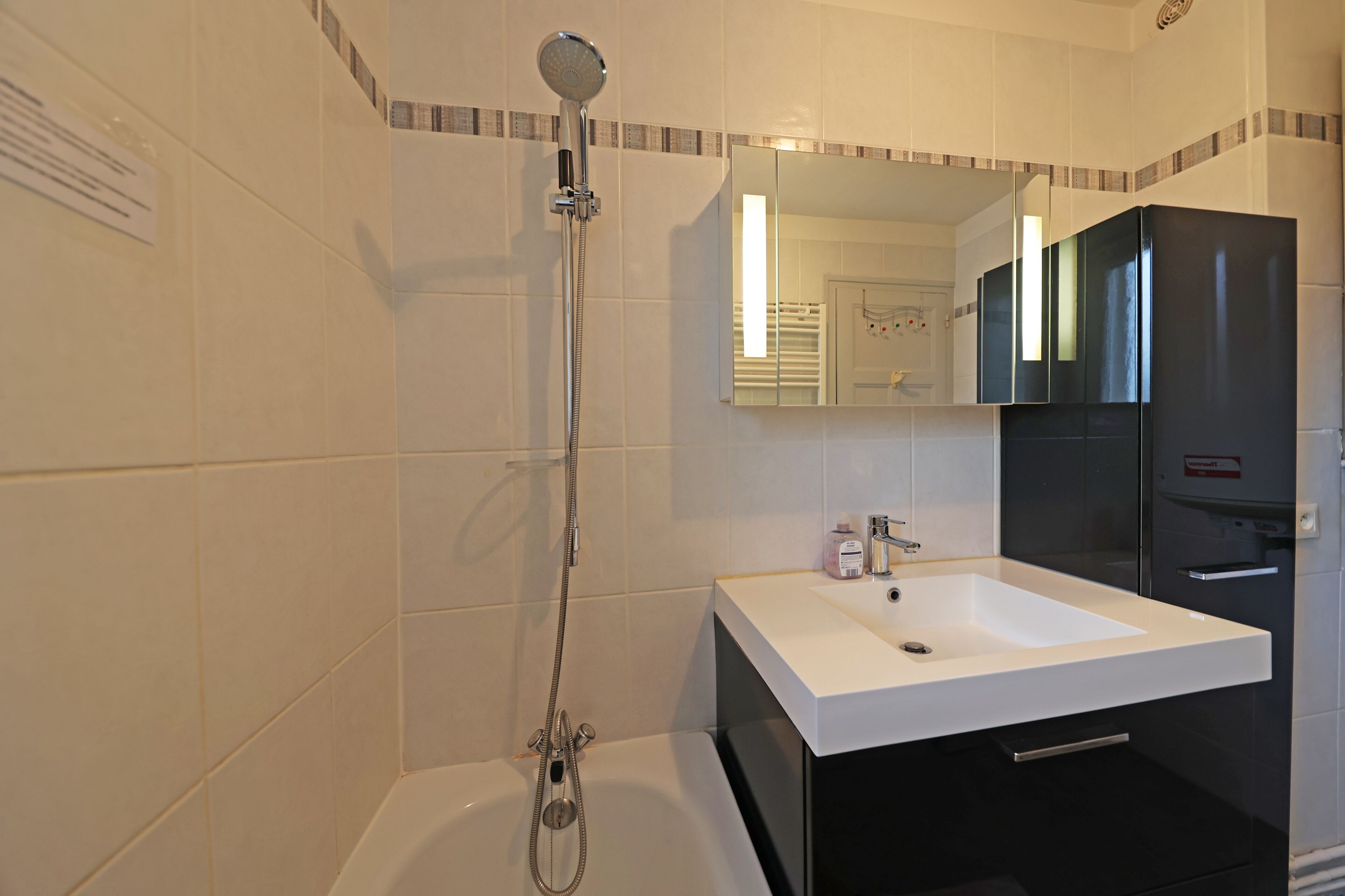 Een badkamer met een bad, een wit wastafel en een spiegel boven de wastafel.