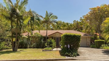 Surrounded by lush greenery, this charming house offers a serene atmosphere and a welcoming front entrance with a small porch area.