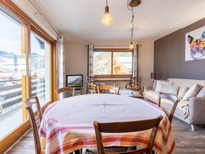 Una habitación acogedora con una mesa de comedor, sillas, un sofá y un televisor.