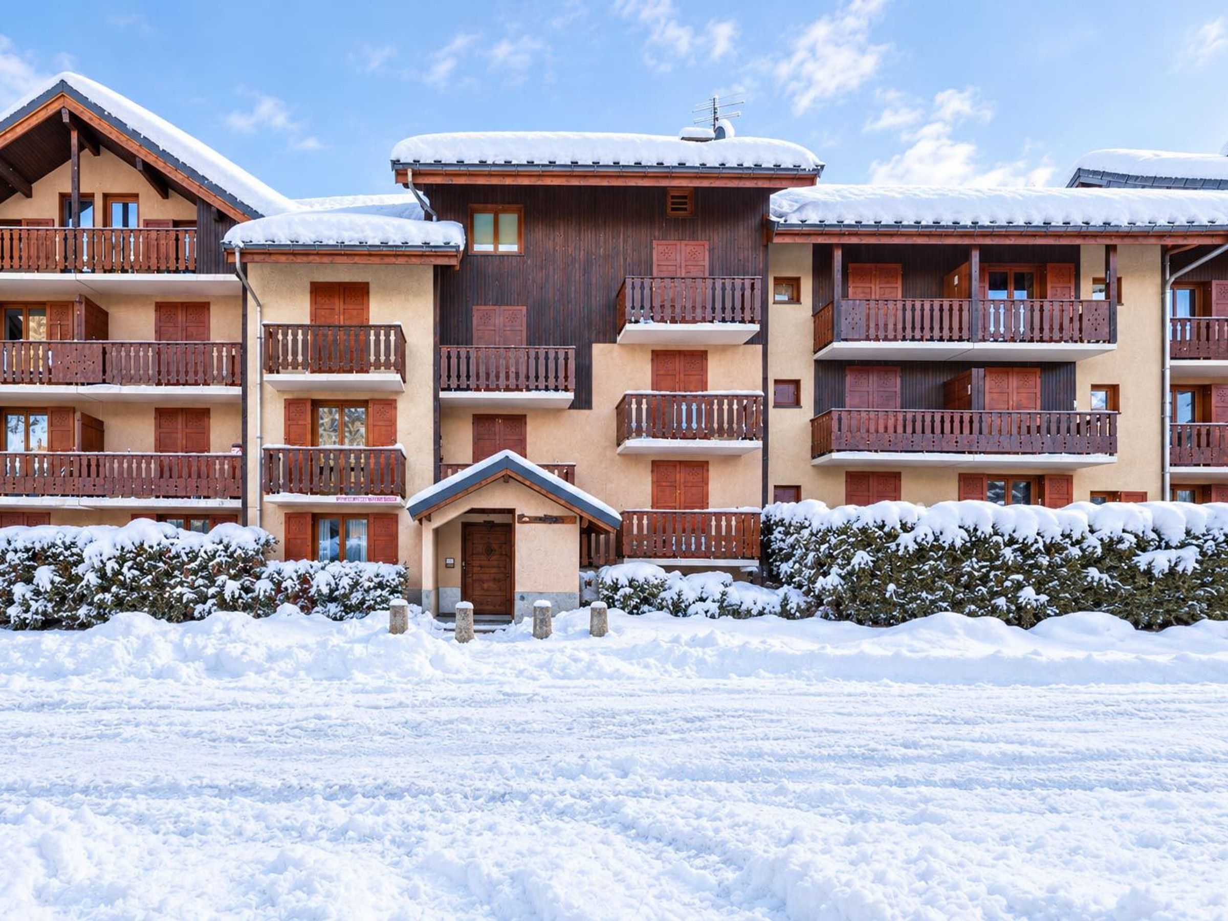 Een meerlaags hotel met balkons, een houten gevel en een besneeuwde omgeving.