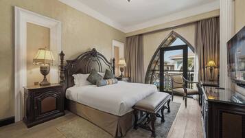 Quarto de hotel com uma cama grande, duas mesas de cabeceira com luminárias, uma cadeira, uma escrivaninha e vista para o exterior.
