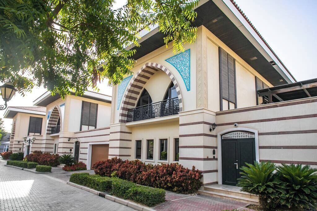 Um edifício moderno com telhado plano, janelas amplas e uma varanda com guarda-corpo.